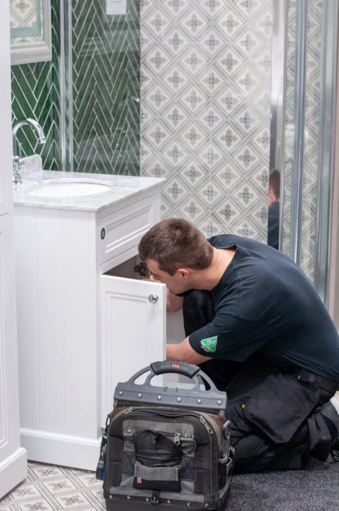 Man checking equipment below bathroom sink