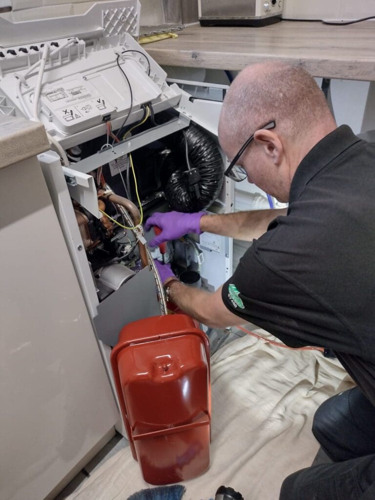 Boiler with exposed parts in kitchen with boiler engineer working