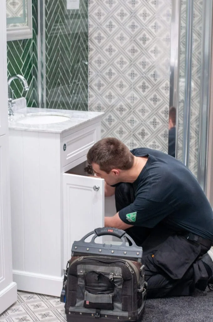 Man checking equipment below bathroom sink