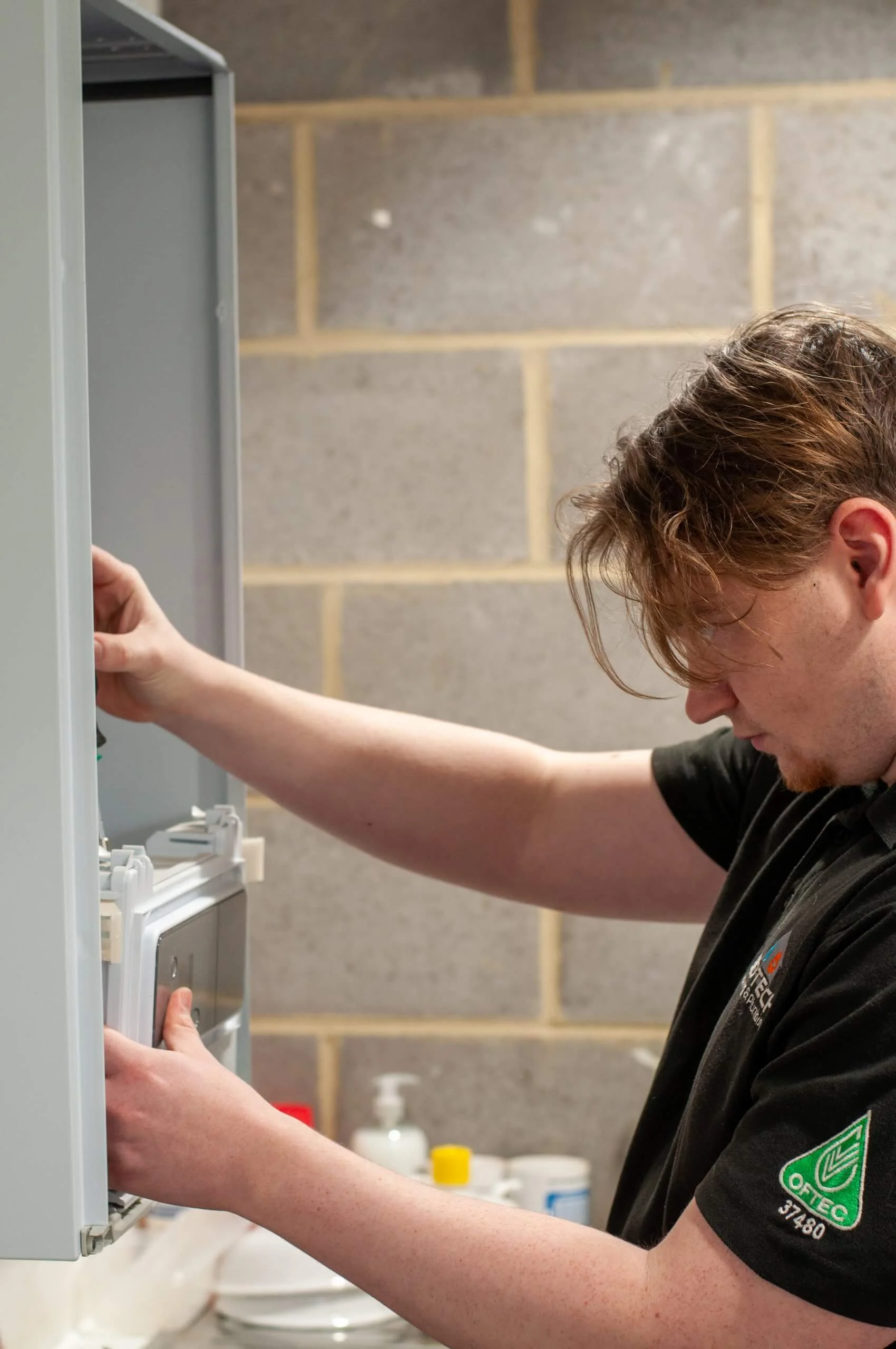 A boilerman working on equipment on the wall